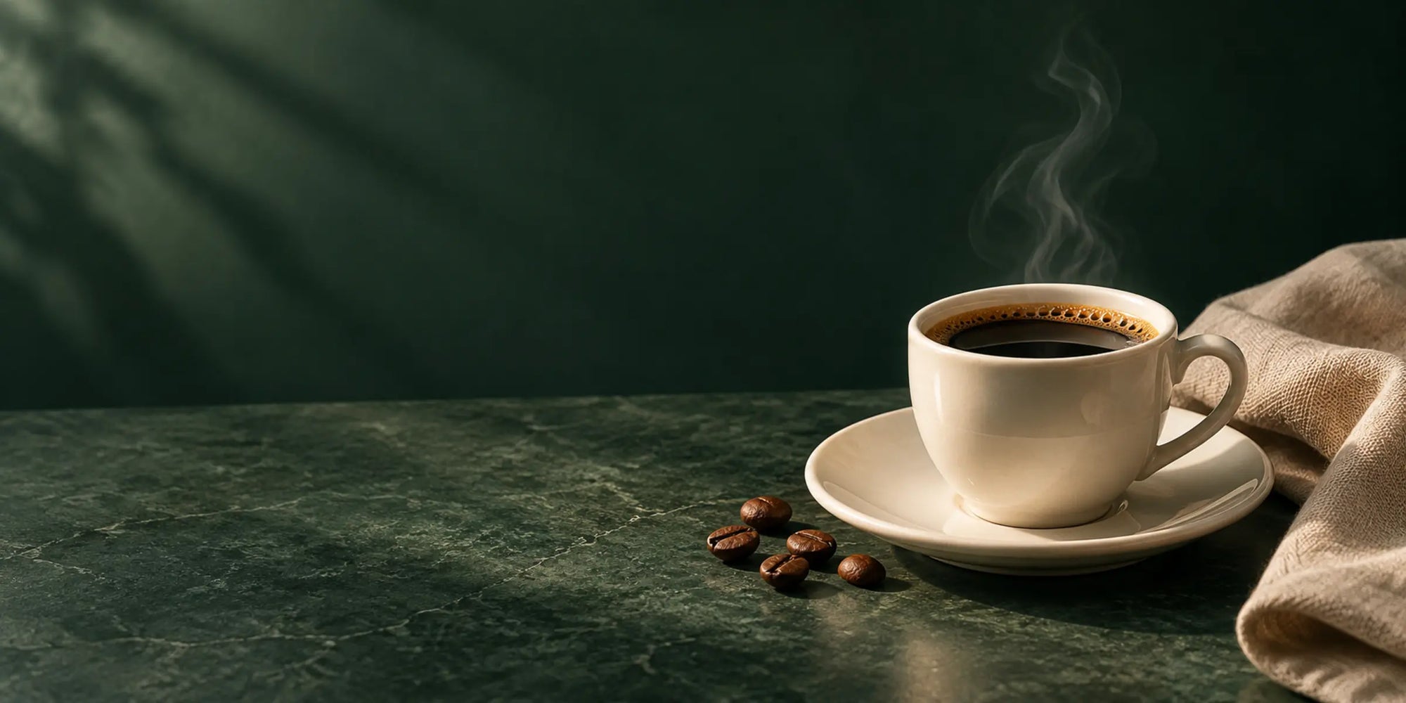 Xícara de café sobre pedra verde, com grãos e tecido natural